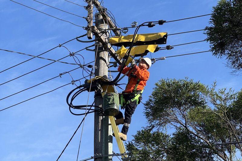 Electrician working on overhead electrical service infrastructure