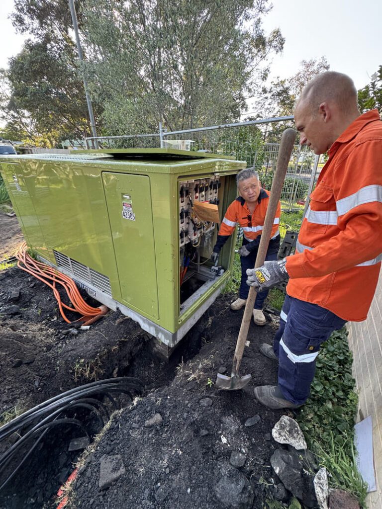 Electricians working on electrical equipment at a site